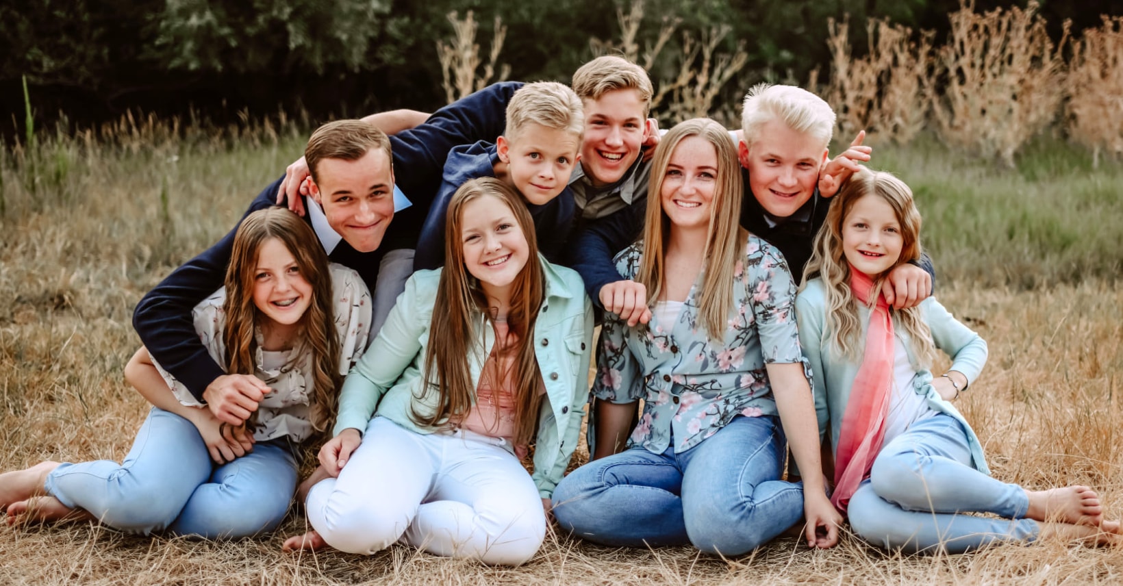 The eight Morrissey children smiling together outdoors in a field
